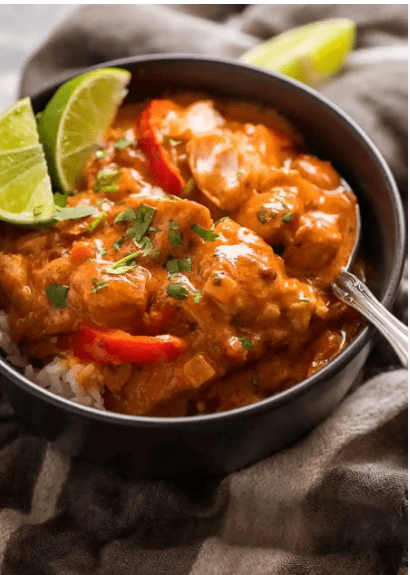 Chicken curry with rice and lime wedges.