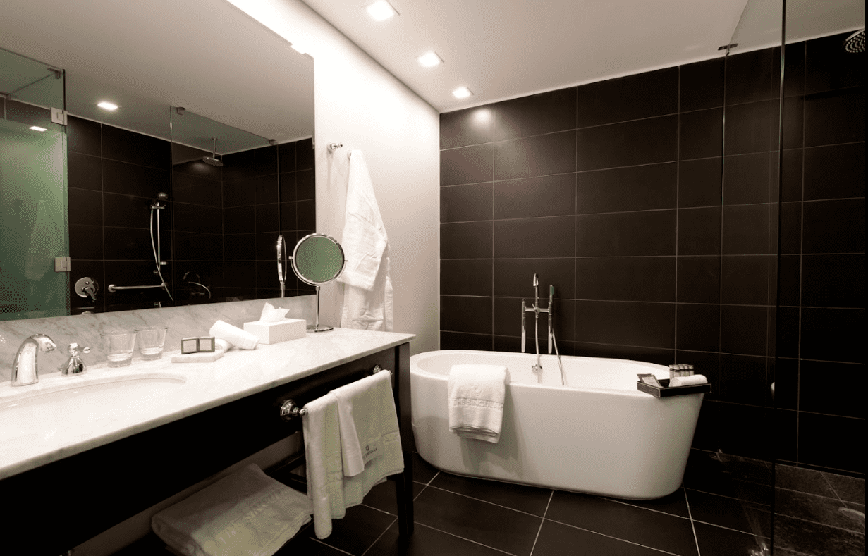 Modern bathroom with white bathtub and black tiles.