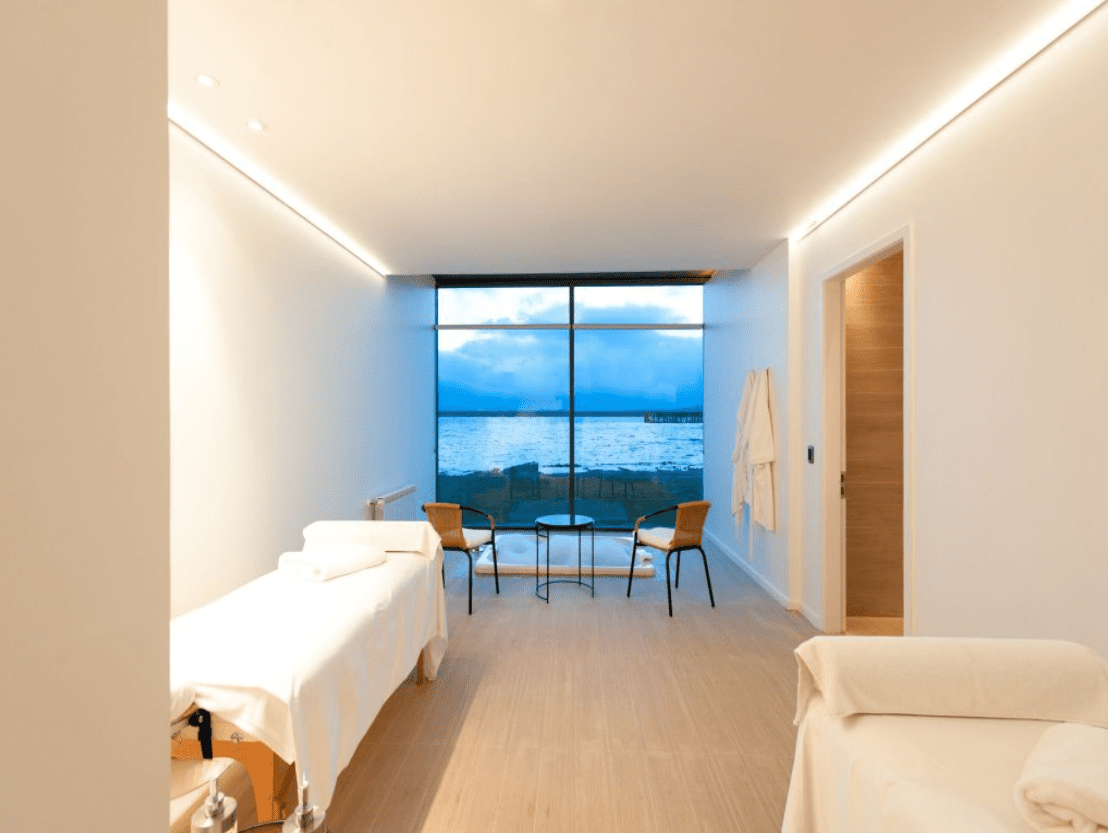 Spa room with ocean view and massage table.