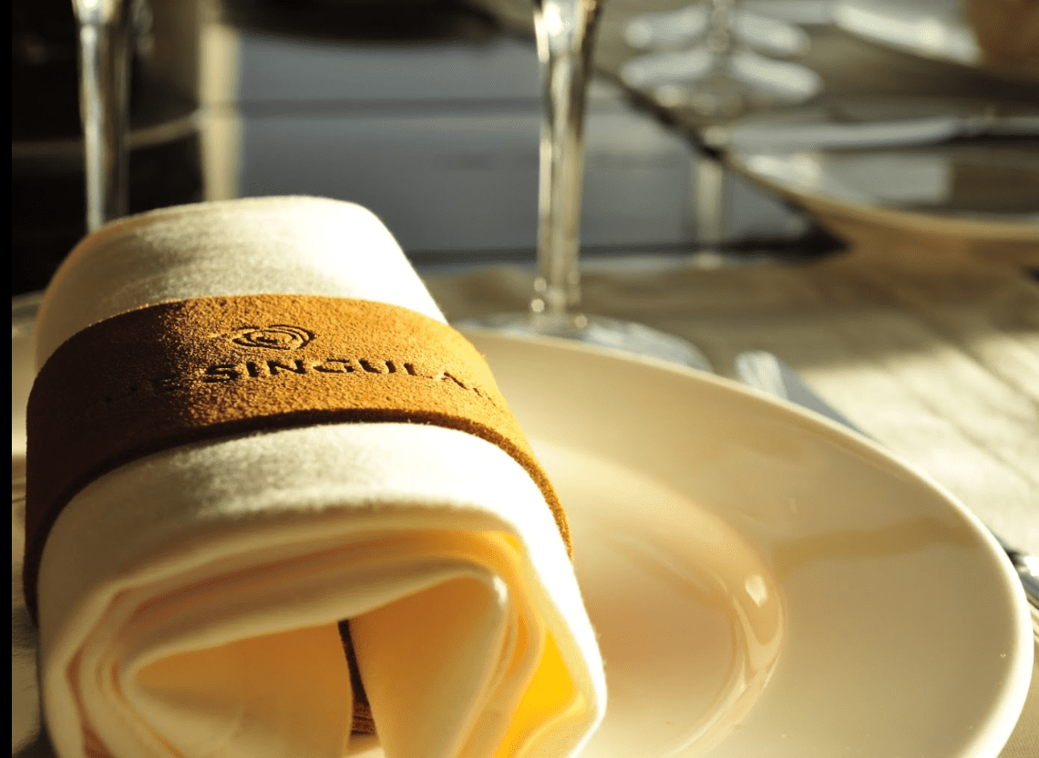 White napkin with leather band on plate.