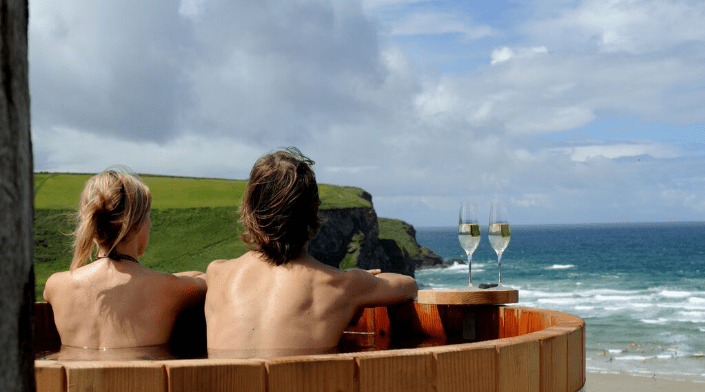 Couple relaxing in hot tub overlooking ocean.