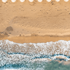 An aerial view of a beach with chairs and umbrellas.