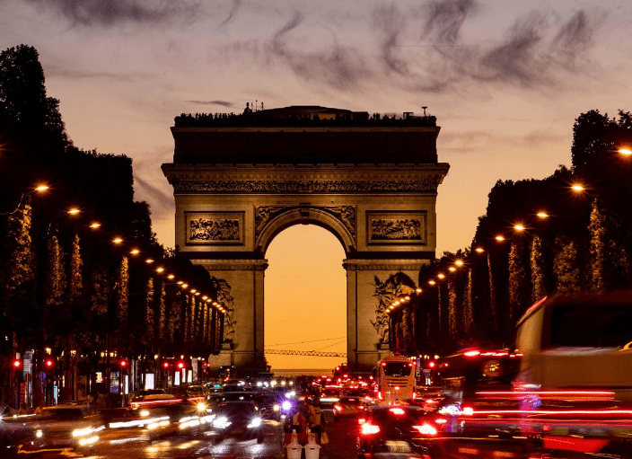 Arc de Triomphe at dusk with traffic.