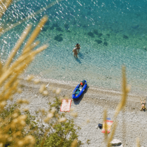 An aerial view of a beach with a person in a canoe.