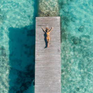 A woman is laying on a dock in the ocean.