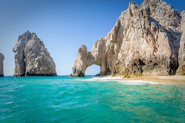 Rocky archway over turquoise ocean.