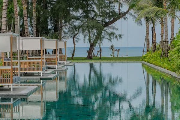 Tropical resort pool with cabanas and ocean view.