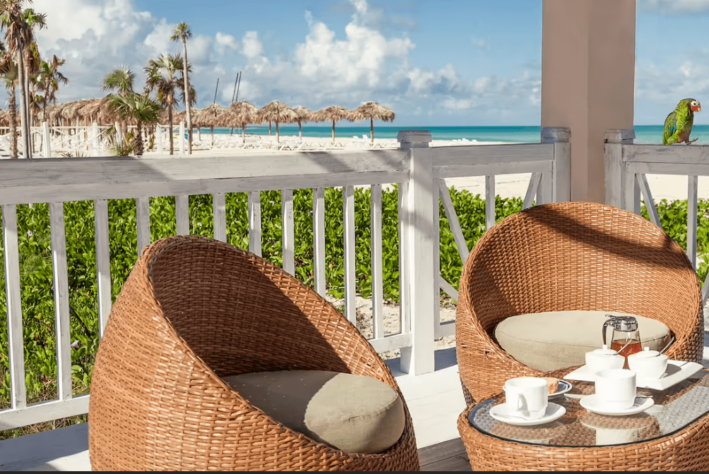 Beachfront patio with wicker chairs and tea.