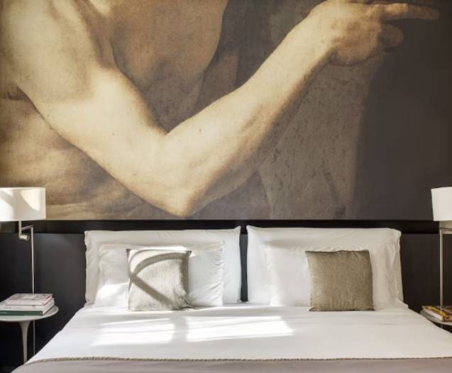 A bed with white linens and a painting.