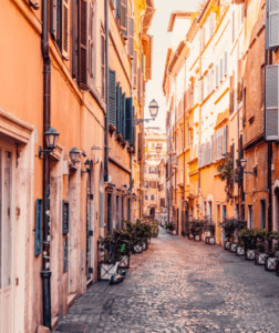 A narrow street with buildings and plants.