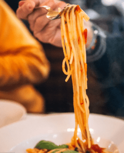 A person holding a fork over spaghetti.