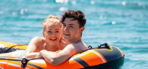 A man and woman are floating on an inflatable raft in the ocean.