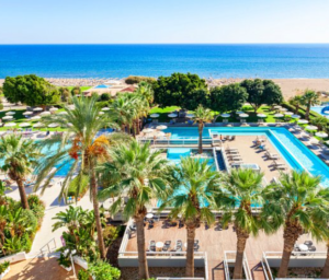 An aerial view of a beach resort with palm trees and a swimming pool.