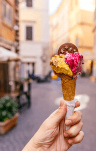 A person holding an ice cream cone in front of a street.