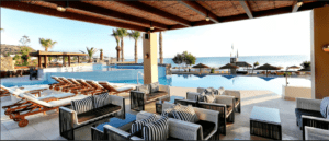 A pool area with lounge chairs and a view of the ocean.