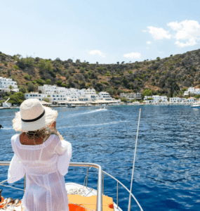 A woman on a boat taking a picture of a village.