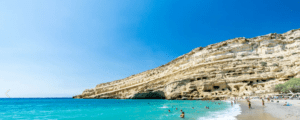 A beach with cliffs and people swimming in the water.