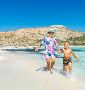 A woman and her son are running on the beach.