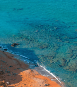 An aerial view of a sandy beach with blue water.