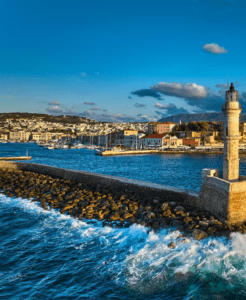 A lighthouse on a rocky shore near a city.