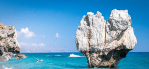 A group of people are swimming in the ocean near a rock formation.