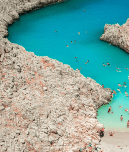 A group of people are swimming in the water near a rocky shore.