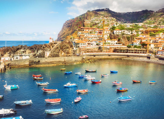 Colorful boats in harbor near hillside town.