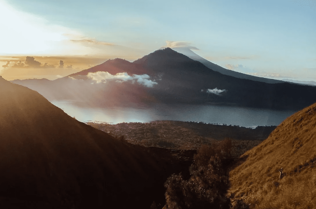 The sun is setting over a mountain and lake in indonesia.