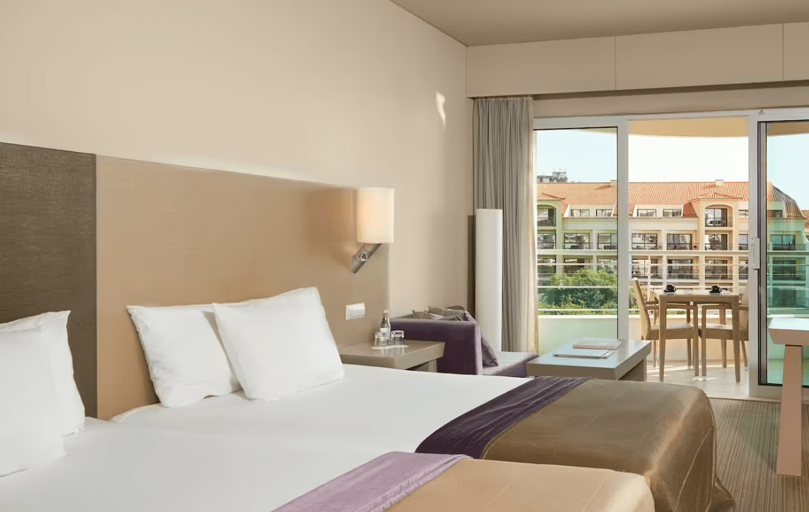 A hotel room with two beds and a balcony.