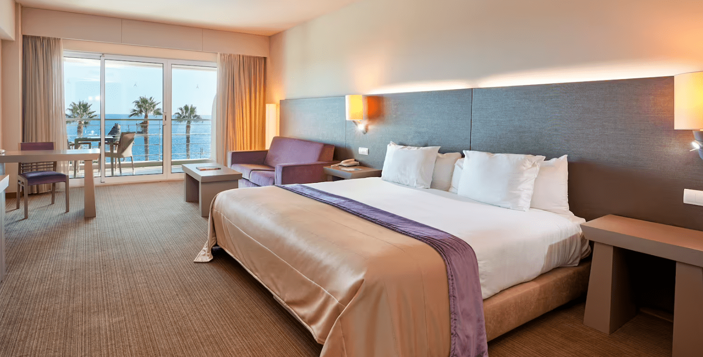 A hotel room with a large bed and a view of the ocean.