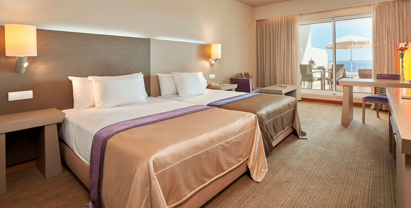 A hotel room with two beds and a view of the ocean.