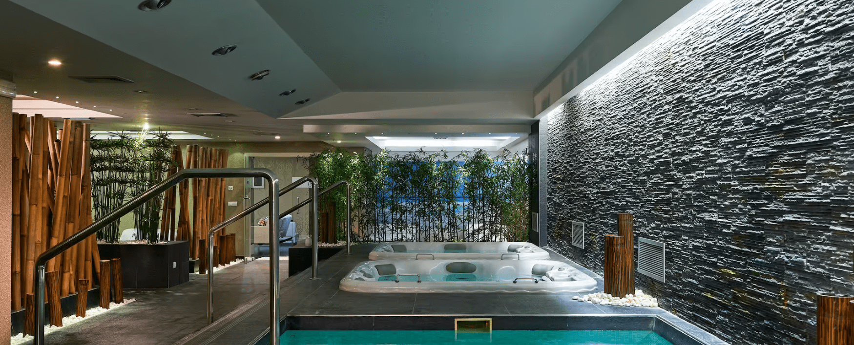 A jacuzzi in a room with a stone wall.