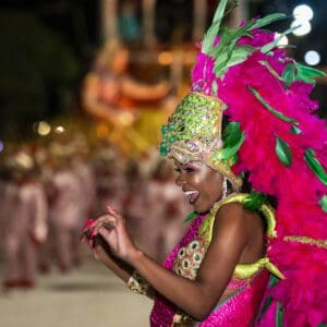 A woman in a colorful costume is dancing in a parade.