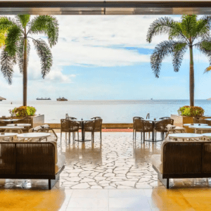 A restaurant with tables and chairs overlooking the ocean.