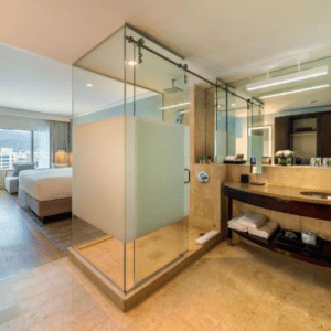 A hotel room with a glass shower and a bed.