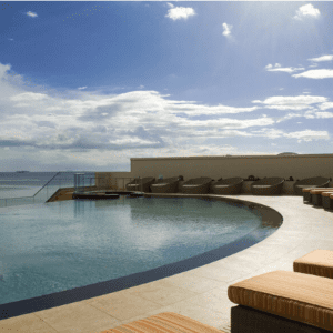 A swimming pool with lounge chairs and a view of the ocean.