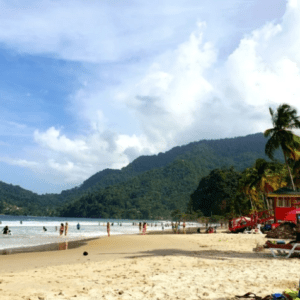 A group of people sitting on a beach with red umbrellas.