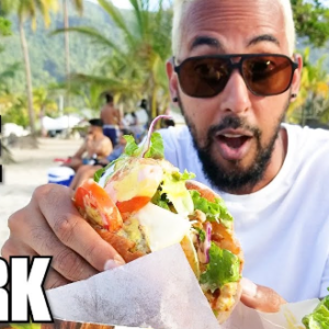 A man is eating a sandwich with the words best bake and shark.