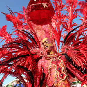 A man in a red costume with feathers on his head.