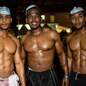 Three shirtless men posing for a photo at night.