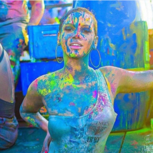 A woman is covered in colorful paint at a festival.