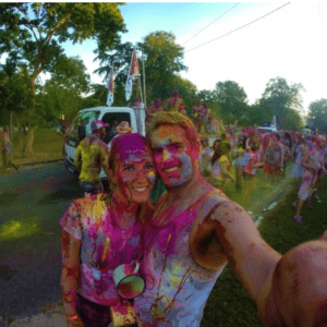 A man and woman taking a selfie at a holi festival.