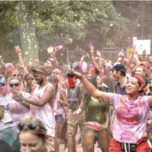 A group of people in a park with colored powder on their faces.