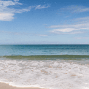 A person on a beach with a surfboard in the water.