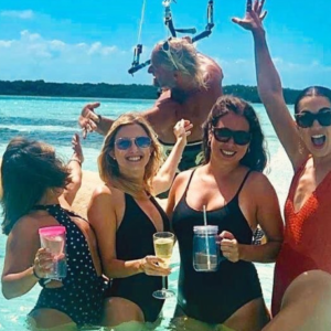 A group of women in swimsuits posing for a picture in the water.