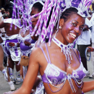 A woman in a purple costume is dancing in a carnival.