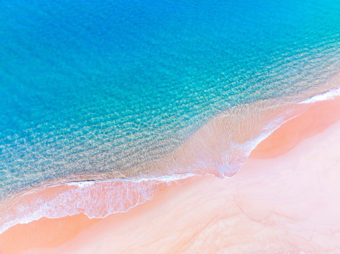 Aerial view of blue ocean and white sand beach.