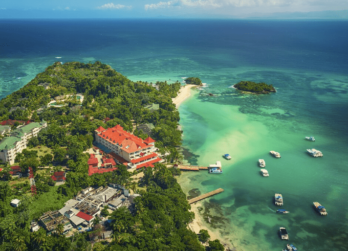 Tropical resort with boats in turquoise water.