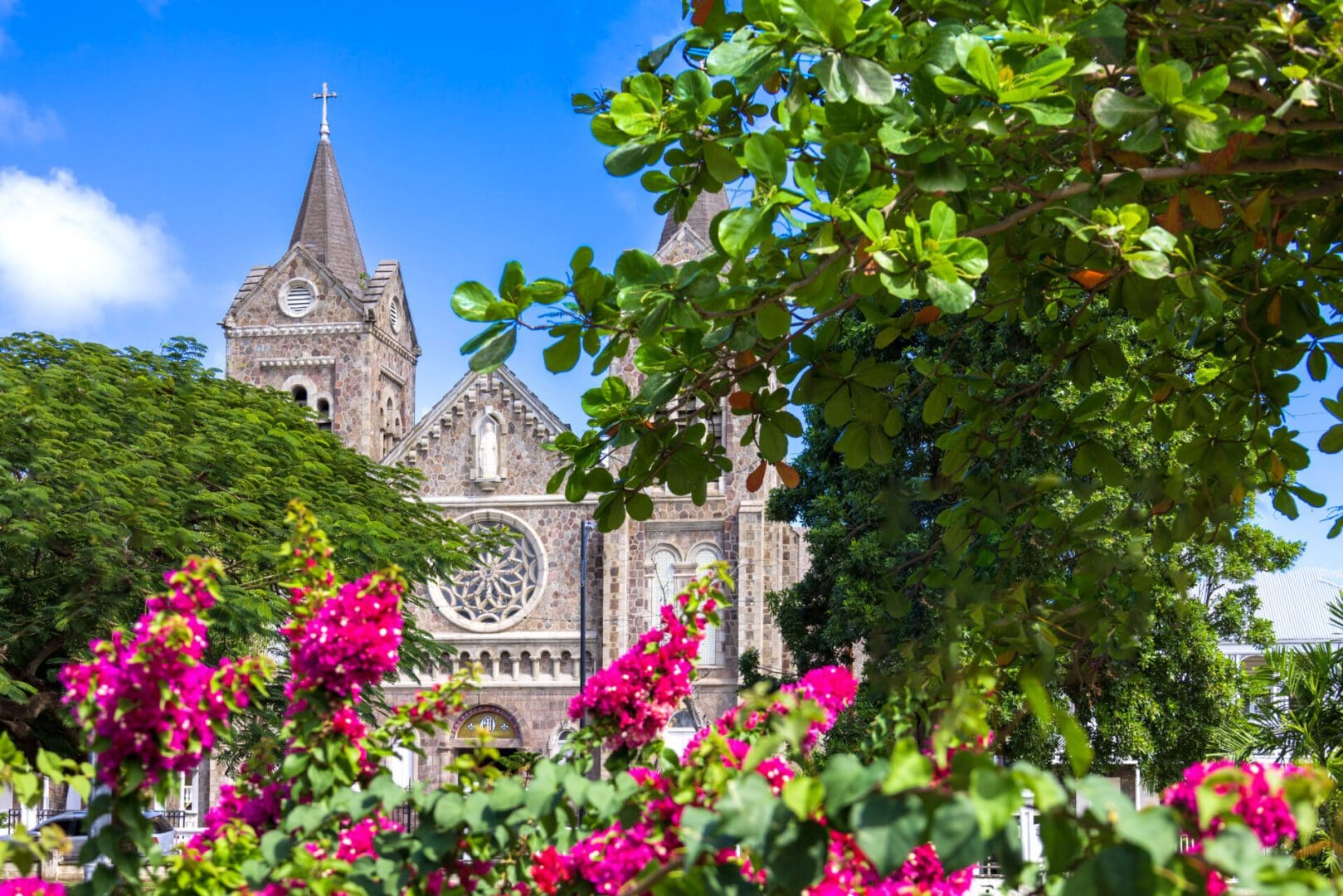 Stone church with pink flowers and trees.