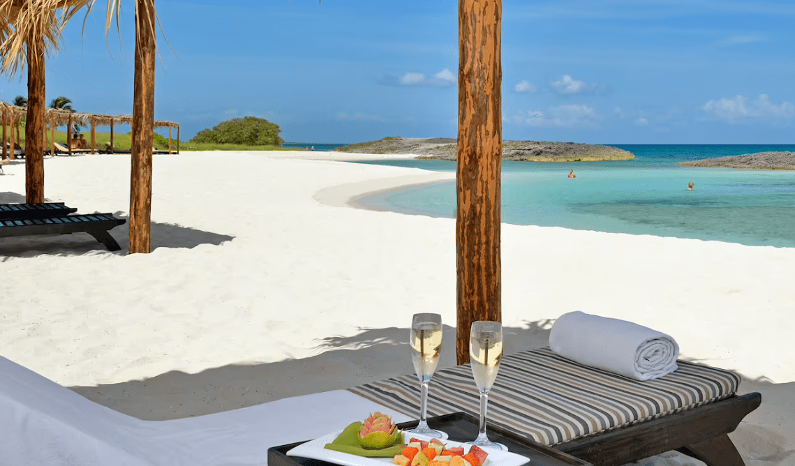 Tropical beach lounge with champagne and fruit.